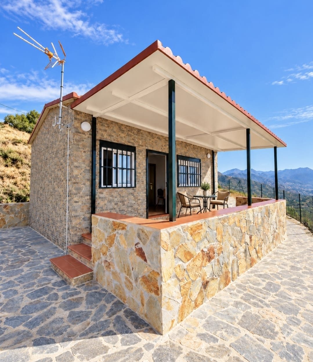 Casa modular con fachada de ladrillo visto, terraza de piedra y vistas a la montaña